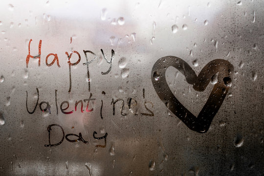 Heart painted inscription Happy Valentines Day on window in Rainy weather