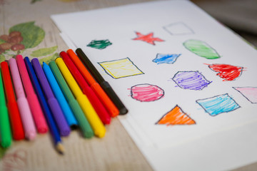 Naklejka premium child painting and coloring figures on white sheet at home. 