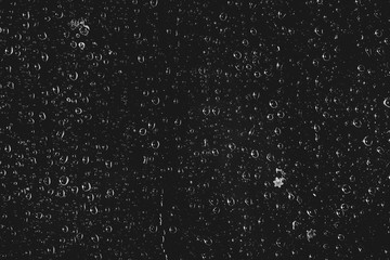 Fototapeta na wymiar Dirty window glass with drops of rain. Atmospheric monochrome dark background with raindrops. Droplets and stains close up. Detailed transparent texture in macro with copy space. Night rainy weather.