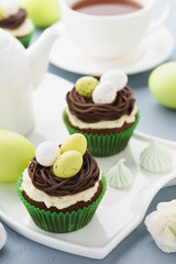 Easter chocolate cupcakes with nest, candy eggs and tea.