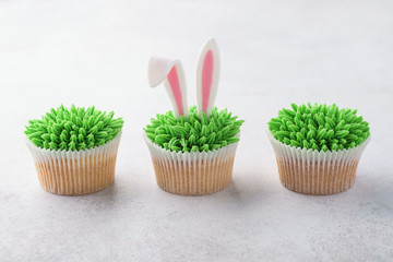 Row of Easter cupcakes decorated with grass and bunny ears.