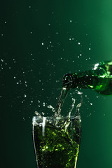 pouring beer into glass with splashes isolated on green, st patrick day concept