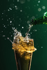 pouring beer into glass with splashes isolated on green, st patrick day concept