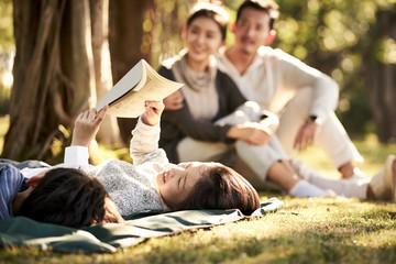 asian family with two children relaxing in park