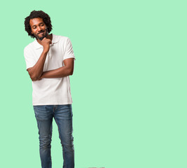 Handsome african american thinking and looking up, confused about an idea, would be trying to find...