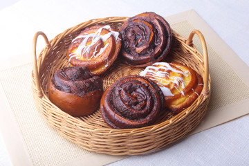 Freshly baked homemade sweet bun or sweet rolls with cinnamon in a wicker basket.