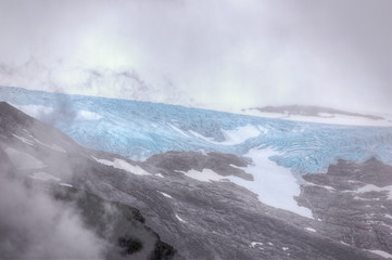 A sneak view through the clouds of the Svartisen glacier seen from the jetty at the Holandsfjord