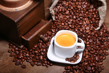 Fresh roasted coffee beans in burlap sack, espresso in cup and grinder on stone background.