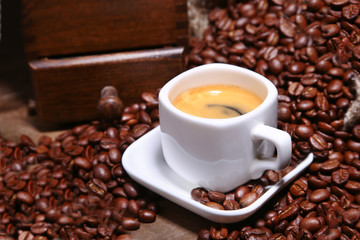Fresh roasted coffee beans in burlap sack, espresso in cup and grinder on stone background.