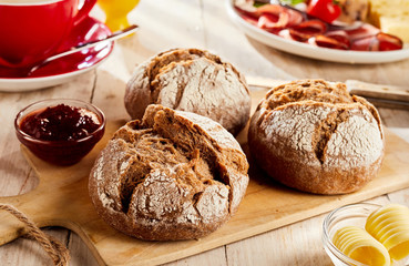 Brown bread buns served on cutting board