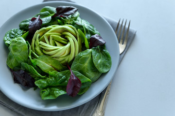 Salad mix with avocado, spinach and beet leaves on gray wooden background. Vegetarian food concept....