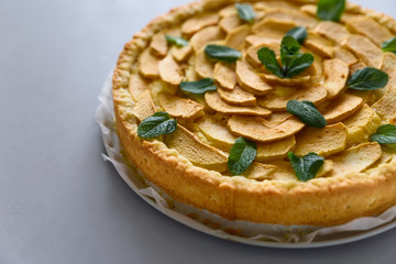Homemade apple pie with cheese decorated mint leaves on gray wooden background. Teatime or...