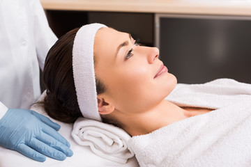 Obraz na płótnie Canvas cosmetician standing near woman laying at beauty salon