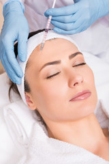 Obraz na płótnie Canvas cosmetologist making injection on woman face at beauty salon