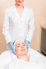 beautician standing behind woman on massage table at beauty salon