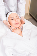 Fototapeta na wymiar cosmetologist doing manual massage on woman face at beauty salon