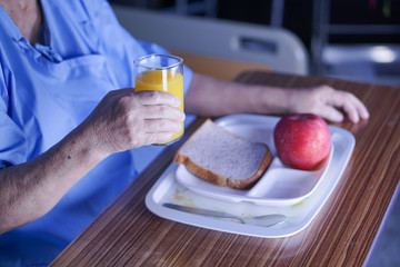 Asian senior or elderly old lady woman patient eating breakfast healthy food with hope and happy while sitting and hungry on bed in hospital.