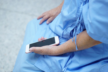 Asian senior or elderly old lady woman patient with credit card talking on the mobile phone while sitting and happy on bed in nursing hospital ward : healthy strong medical concept 
