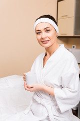 woman sitting and holding cup in hand at beauty salon