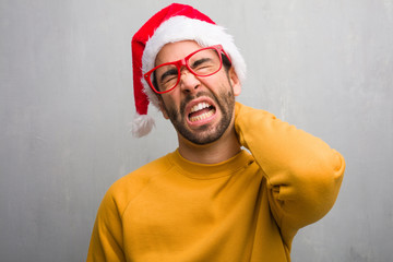 Young man celebrating christmas day holding gifts suffering neck pain