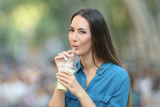 Woman drinking milk shake in the street looking at you
