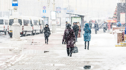 Obraz premium Blizzard in an Urban Environment. Crowd of Rushing People in Snowfall. Abstract Blurry Winter Weather Background.