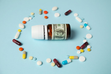 Medical pills on blue background with money, the cost of treatment, expensive medicine. Spring allergy, medical insurance.