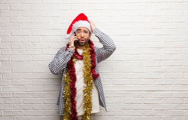 Young man sitting with gifts celebrating christmas worried and overwhelmed