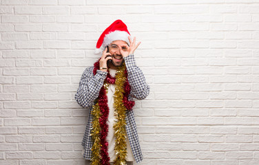 Young man sitting with gifts celebrating christmas confident doing ok gesture on eye