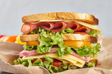 Sandwich with ham cheese on paper, on wooden background