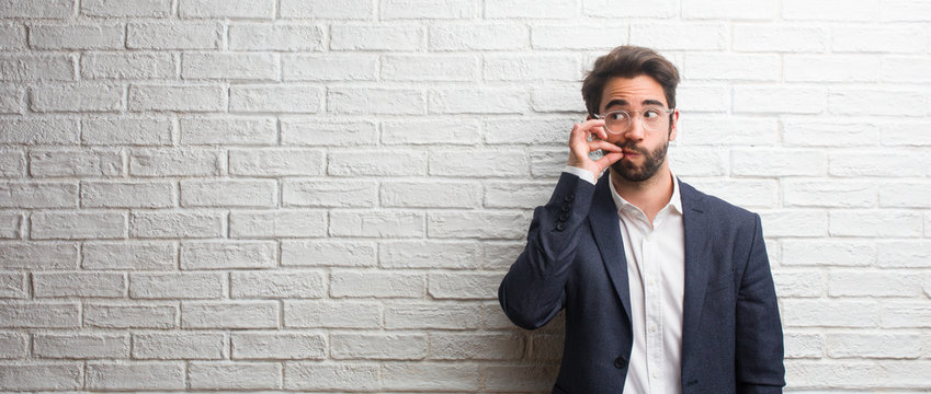 Young friendly business man keeping a secret or asking for silence, serious face, obedience concept
