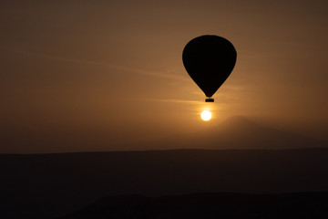 Hot air balloons flying over spectacular Cappadocia on sunset.