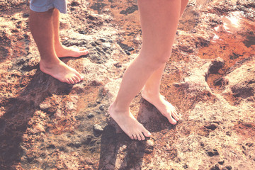 Male and female feet standing on a wet stone.