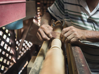 Hands of carpenter turning wood on lathe machine in carpentry workshop