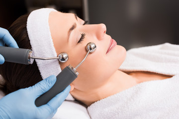 beautician doing lifting massage on woman face at beauty salon