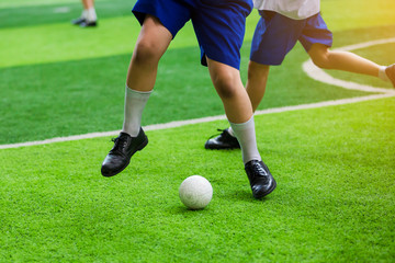 Obraz premium Asian student play plastic soccer ball on green artificial turf