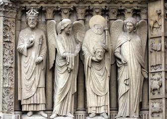 Fototapeta na wymiar Paris, Notre-Dame cathedral, portal of the Virgin. From left to right: Emperor Constantine, an angel, Saint Denis holding his head, and another angel.
