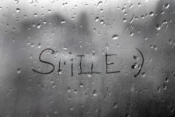 Handmade word smile on the wet glass