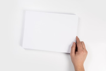Hand holding white blank paper sheet mockup, isolated. Arm in shirt hold clear brochure template mock up.