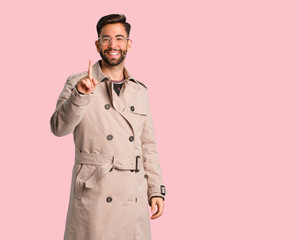 Young man wearing trench coat showing number one