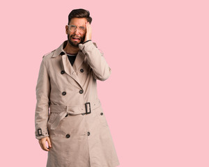 Young man wearing trench coat desperate and sad