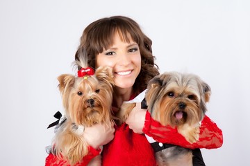 young beautiful woman with two yorkshire terriers in photo studio. dogs in costumes for boy and girl, woman in red dress