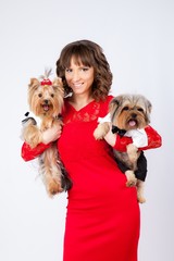 young beautiful woman with two yorkshire terriers in photo studio. dogs in costumes for boy and girl, woman in red dress