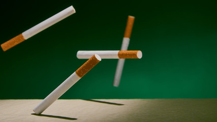 Cigarettes fall on a green background.