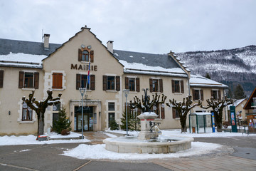 Place centrale de Lans en Vercors en Isère avec vue sur le mairie et la fontaine d'eau givrée.