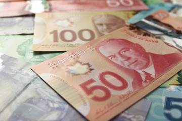 Paper notes from Canada. Dollar. Different amounts of bills. Full frame of bills spread on table and assorted amounts.