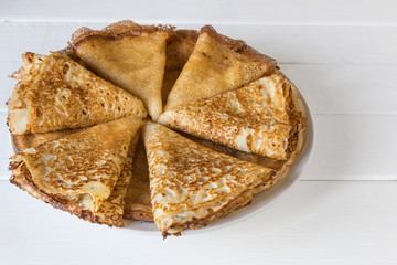 A pile of pancakes with honey for breakfast. White table