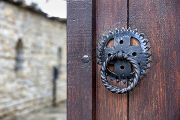Front wooden door with a knocker, open to blur an inside yard