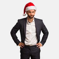 Young business man wearing santa hat scolding someone very angry