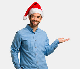 Young man wearing santa hat holding something with hand